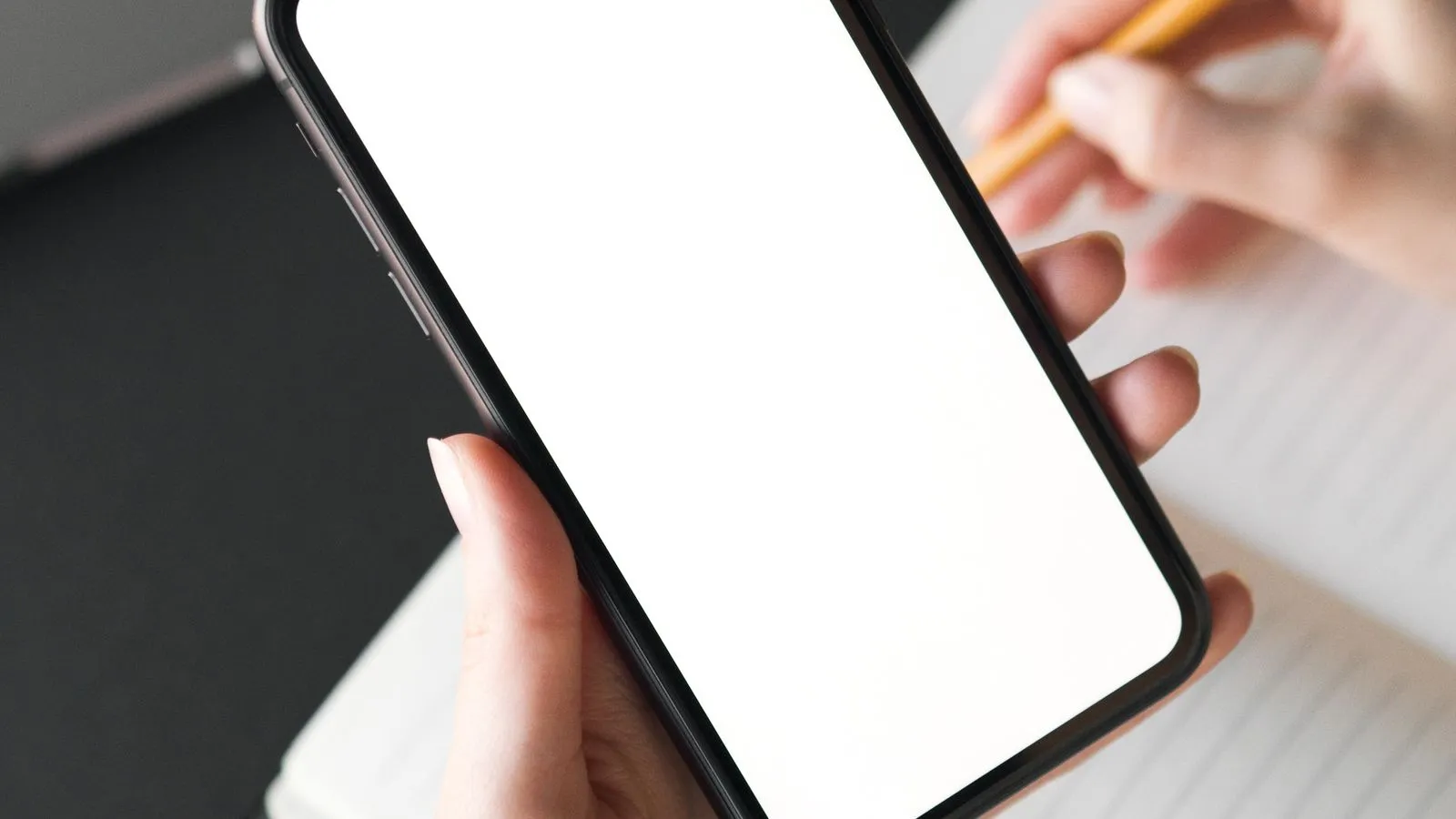 Móvil sobre un escritorio junto a una notificación de almacenamiento lleno, con apps y ajustes al fondo